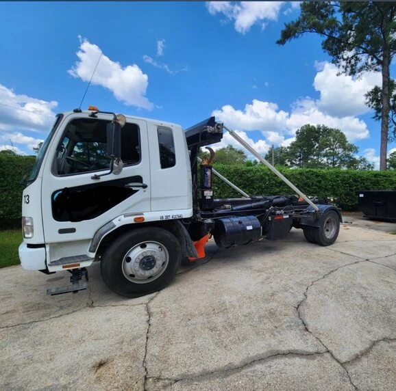 White hook lift truck used for fast dumpster delivery and pickup in Saginaw Michigan