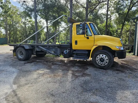 Yellow roll-off dumpster truck used for yard waste and cleanup projects in Saginaw Michigan