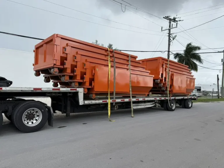 Multiple Saginaw roll off dumpsters loaded on a truck for local delivery