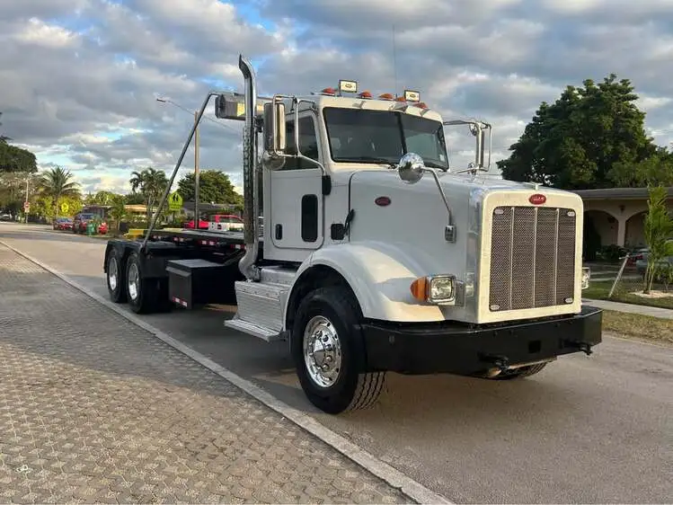 White heavy-duty roll-off dumpster truck parked on roadside for professional dumpster rental service in Saginaw Michigan